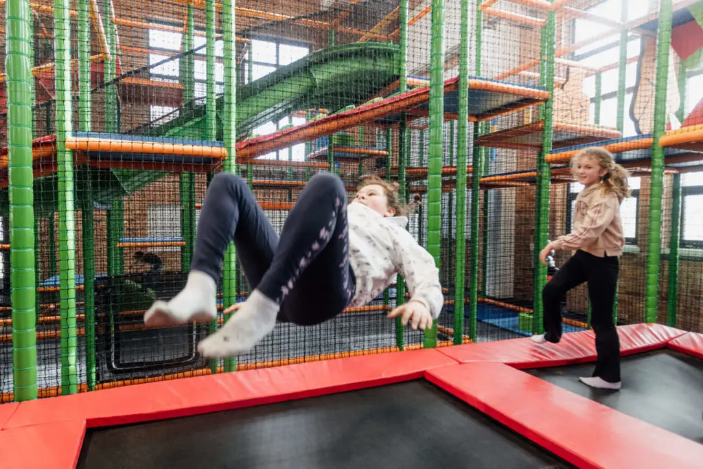 Kinder springen auf einem Trampolin in einem Indoorspielplatz und genießen den Spaß.